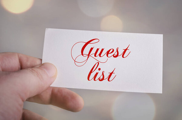 Guest list card in hand with bokeh lights background