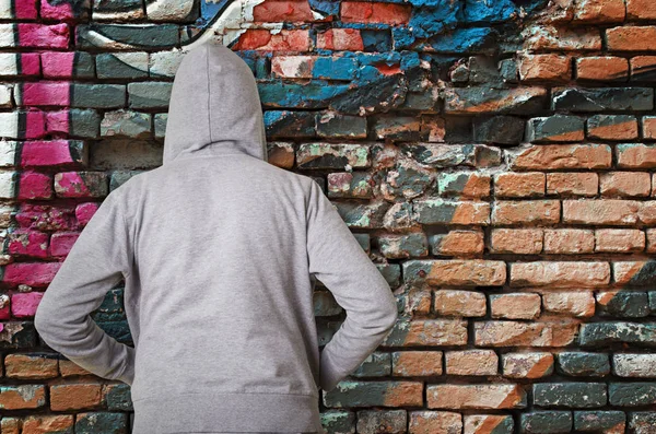 Rear view of hooded man against wall with graffiti