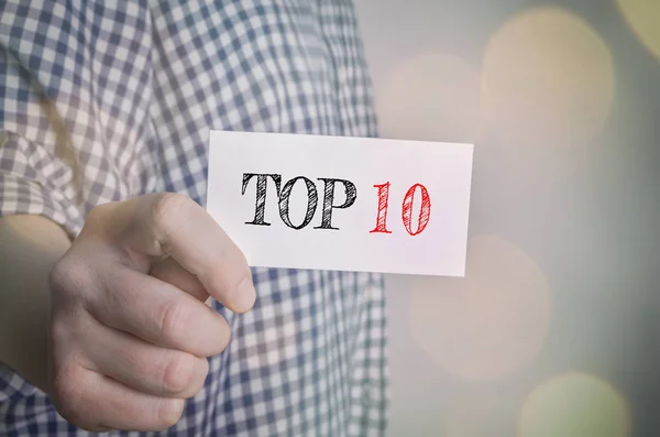 Top 10 carta in mano con sfondo luci bokeh — Foto Stock