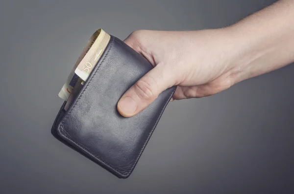 Δερμάτινο πορτοφόλι στο χέρι που απομονώνονται σε σκούρο φόντο — Φωτογραφία Αρχείου