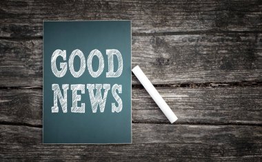 Ahşap arka plan bir kara tahta üzerinde yazılmış iyi haber metni