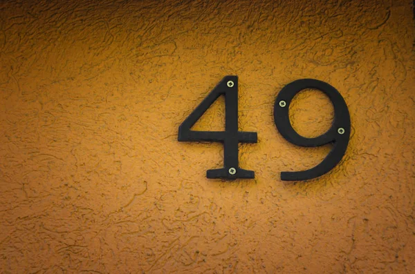 Domovní číslo čtyřicet devět (49) na oranžové betonová zeď — Stock fotografie