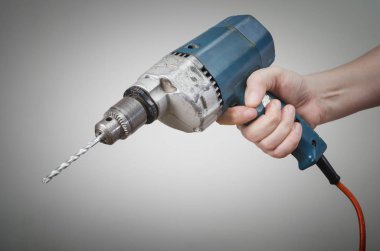Bir erkek eli ile elektrikli matkap gri arka plan üzerinde.