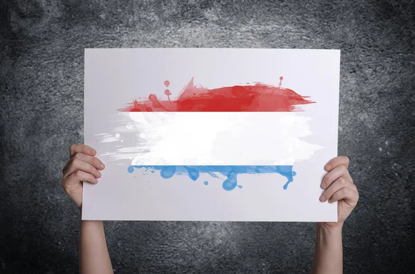 Lucembursko vlajky na bílé karty v rukou. Pojem vlastenectví — Stock fotografie