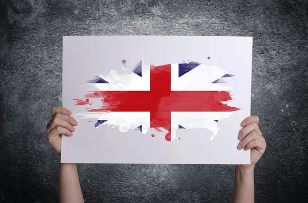 Britse vlag op witte kaart in handen. Concept van patriottisme. — Stockfoto