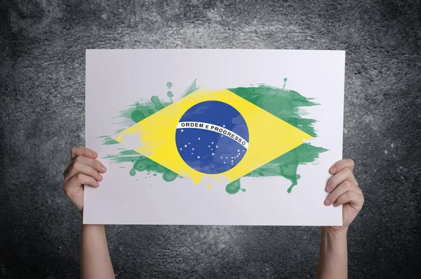 Bandeira do Brasil em cartão branco nas mãos. Conceito de patriotismo . — Fotografia de Stock