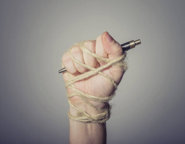 Hand with pen tied with rope.