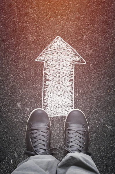 Pair of male sneakers on the asphalt road with drawn direction arrow. — Stock Photo, Image