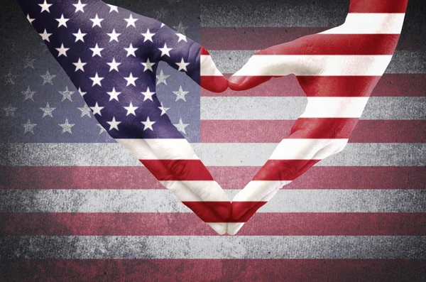 Hands of a young man forming a heart patterned with an American flag — Stock Photo, Image