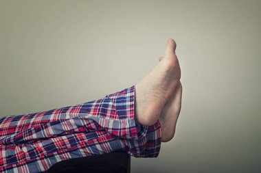 Genç bir adamın bacakları damalı pijama closeup. Evde koltukta oturan adam.