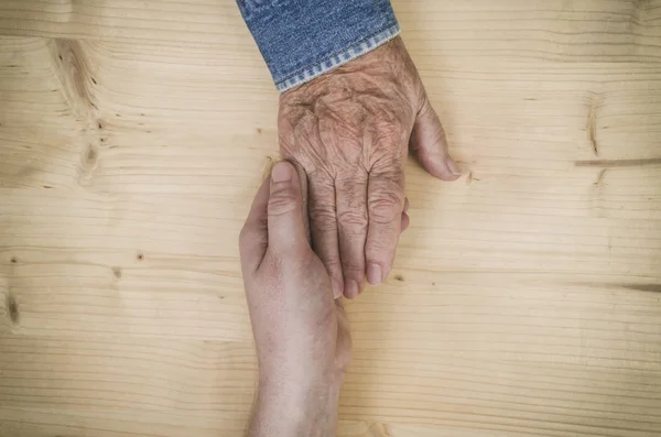 Male hand holds the hand of an elderly woman. Lots of texture and character in the old ladies hand. — Stock Photo, Image