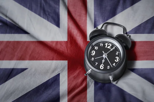 UK tijd. Wekker met Britse vlag achtergrond, bovenaanzicht. — Stockfoto
