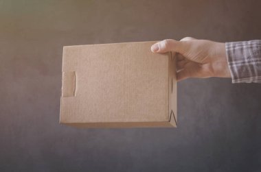 Erkek eli ile koyu arka plan üzerine karton kutu.