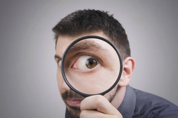 Portrait of a curious man looking through magnifying glass — Stock Photo, Image