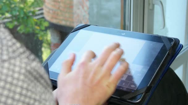 Tiener zitten door een venster met behulp van zijn Tablet — Stockvideo