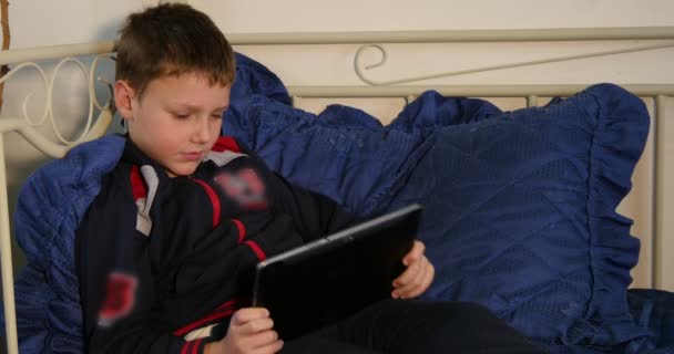 Мальчик играет в игру, лежа на кровати — стоковое видео