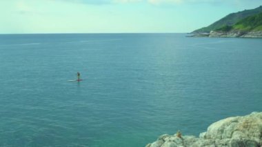 Adam Paddleboard Denizi üzerinde duruyor