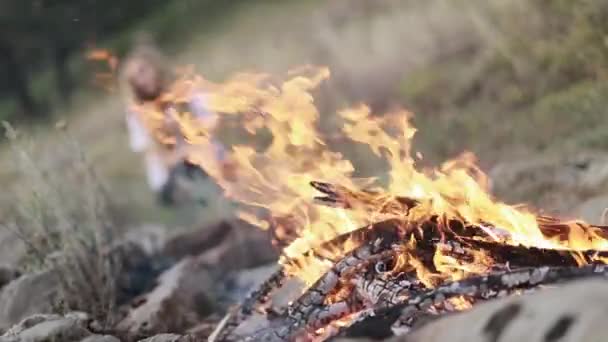 Jeune femme assise près du feu de camp 