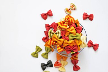 Komik çok renkli makarna. Güzel makarna bir kelebek şeklinde. Beyaz arka plan üzerinde izole orijinal İtalyan makarna. Beyaz bir arka plan şeffaf bir plaka üzerinde yanardöner kıvırcık makarna.