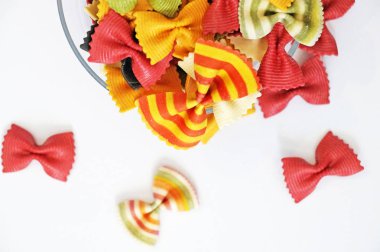 Komik çok renkli makarna. Güzel makarna bir kelebek şeklinde. Beyaz arka plan üzerinde izole orijinal İtalyan makarna. Beyaz bir arka plan şeffaf bir plaka üzerinde yanardöner kıvırcık makarna.