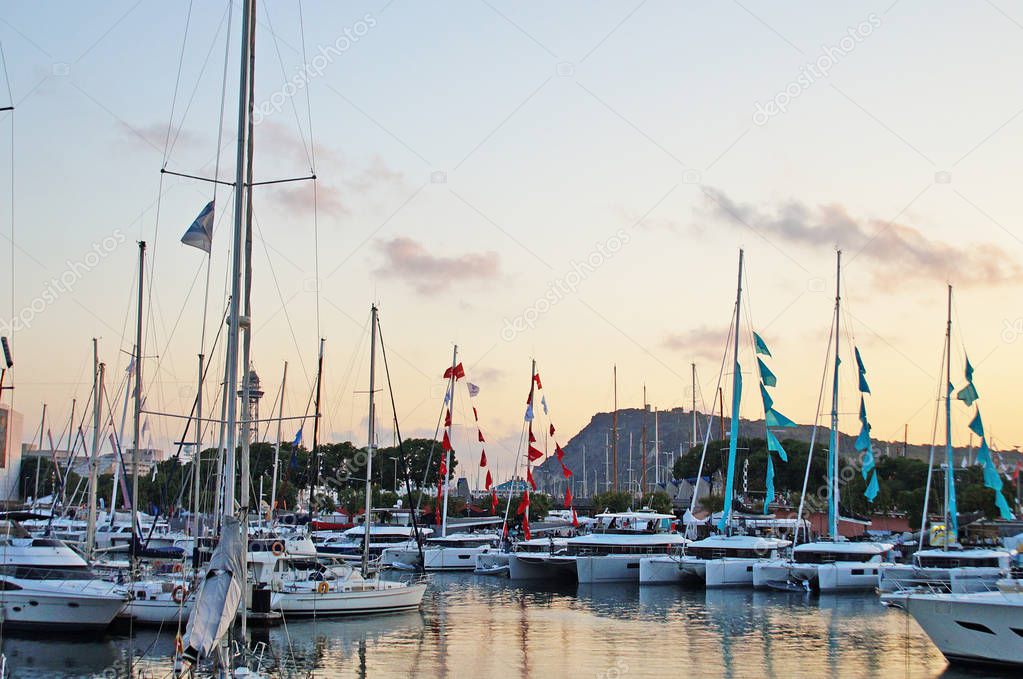 The bay with yachts is surrounded by low hills. Sunset over the bay. Harbor with yachts in Barcelona. Marina for yachts in the Mediterranean.