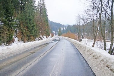 Dağ yolundan. Karla kaplı dağlar ve iğne yapraklı orman arasında uzanan mesafe, asfalt yol gider.                               