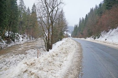 Dağ yolundan. Karla kaplı dağlar ve iğne yapraklı orman arasında uzanan mesafe, asfalt yol gider.                               