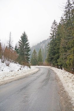 Dağ yolundan. Karla kaplı dağlar ve iğne yapraklı orman arasında uzanan mesafe, asfalt yol gider.                               