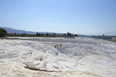 Kaplıca Pamukale, sıcak, sıcak bir günde çevredeki bozkırlarında ve alanlar üzerinde yükselir. Türkiye'de Pamukale kireçtaşı havzaları.