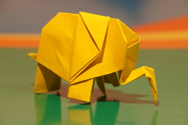 Origami is the elephant. Paper elephant on a colored background. Japanese art.