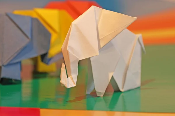 Origami elephants. Colored paper elephants on a multi-colored background. Japanese art.