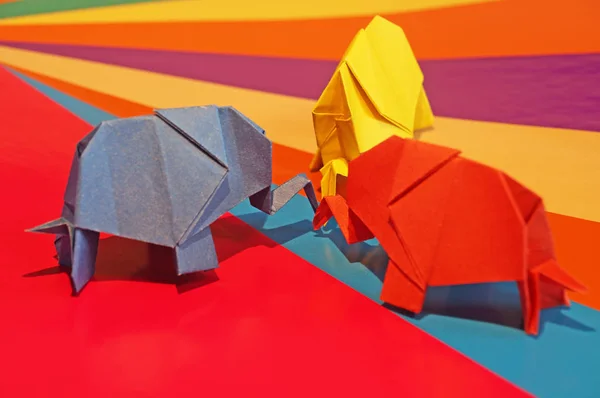 Origami elephants. Colored paper elephants on a multi-colored background. Japanese art.
