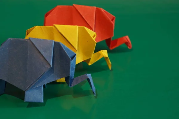 Origami elephants. Colored paper elephants on a multi-colored background. Japanese art.