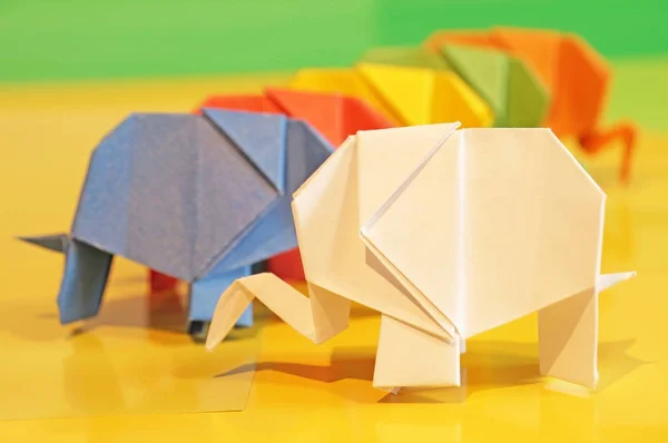 Origami elephants. Colored paper elephants on a multi-colored background. Japanese art.