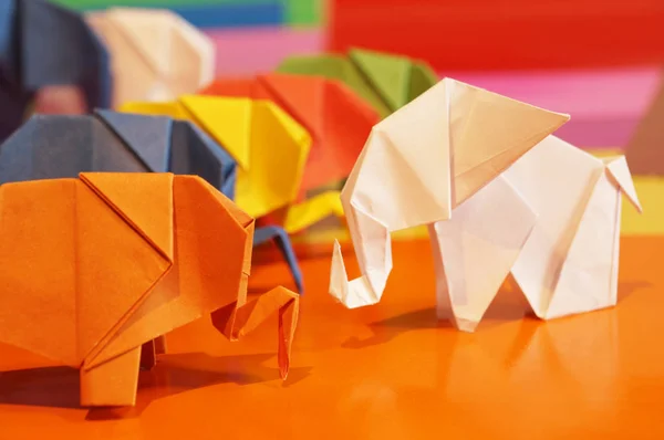 White origami of elephants. Colored paper elephants on a multicolored background. Japanese art.