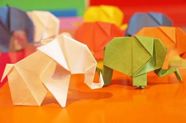 White origami of elephants. Colored paper elephants on a multicolored background. Japanese art.