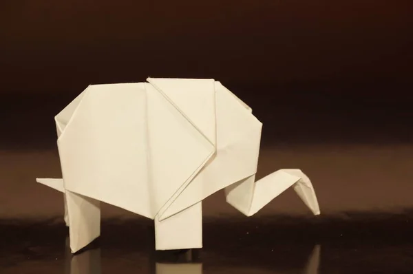 White origami of elephants. White paper elephant on a colored background. Japanese art.