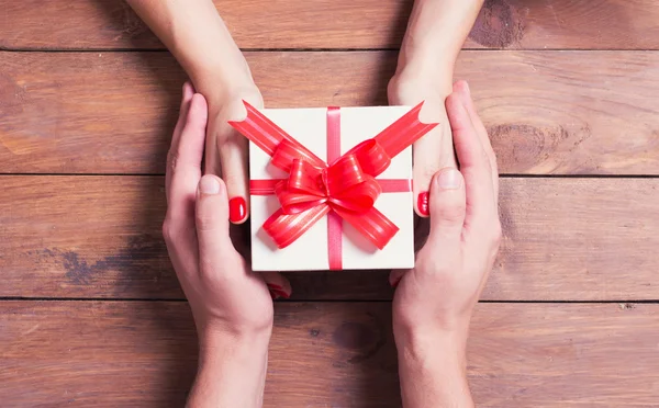 Frau mit Mann hält ein Weihnachtsgeschenk in der Hand — Stockfoto