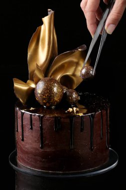 İzole, süslü çikolatalı kek, siyah arka plan. İnci el
