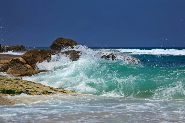 Las olas rompiendo en una playa pedregosa, formando un aerosol — Foto de Stock