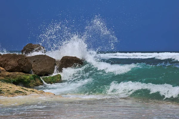Las olas rompiendo en una playa pedregosa, formando un aerosol — Foto de Stock