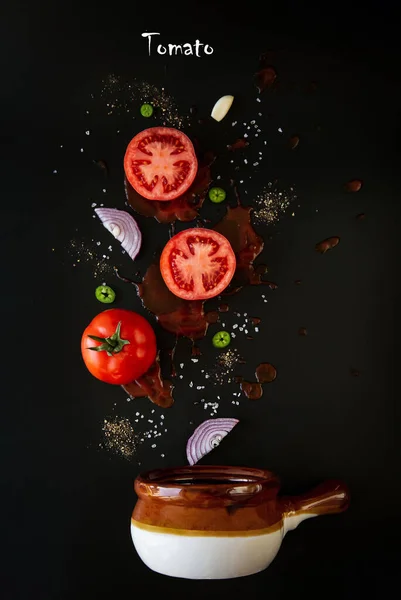 Raw ingredients for cooking tomato sauce or soup  -  fresh , raw tomato, red onion, hot end black pepper, salt. Vegetarian lunch. Healthy food. Concept promotional flyer and poster. Black background.
