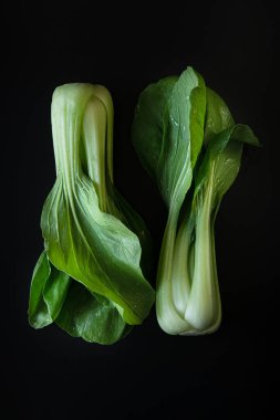 İki tam Bok Choy, ya da Çin lahana yeşillikleri siyah arka planda izole edilmiş. 