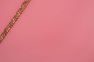 Pembe arka planda izole edilmiş altın kolye.