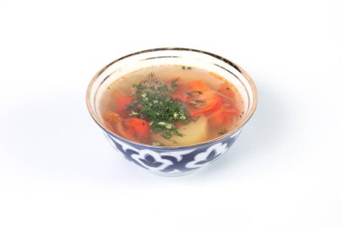 Beyaz arka planda patates ve sebzeli tavuk çorbası.