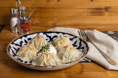 Menü ve ağ için kahverengi tabakta ekşi kremalı Manti.