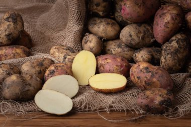 Ahşap arka planda taze, kirli, beyaz ve kırmızı patatesler. Vejetaryen yemeği..