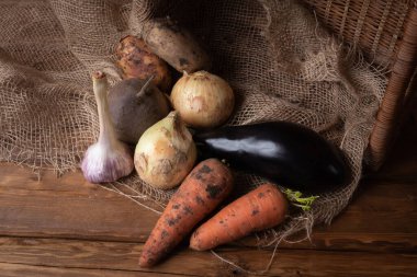 Tahta zeminde taze çiğ patates, soğan, havuç, sarımsak ve patlıcan. Vejetaryen yemeği..