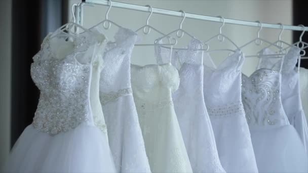 Свадебные платья висят на стойках — стоковое видео