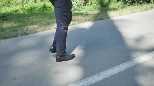 Человек в костюме идет по дороге медленно — стоковое видео